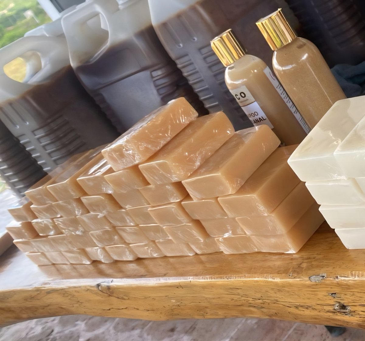 Artisanal Batana Oil soap bars and hair care bottles with gold caps arranged on rustic wood